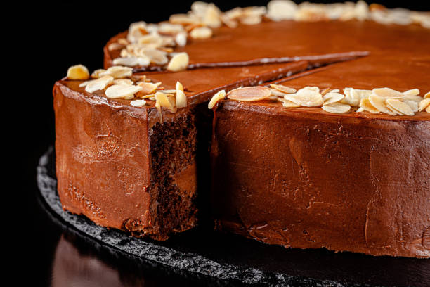 istock Modern pastry. Chocolate cake with nuts, almonds and peanut butter. Cake on a black background. background image, copy space text 1211965519