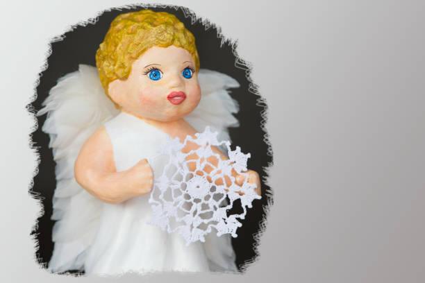 Doll angel with a knitted snowflake close-up Doll angel with a knitted snowflake close-up winged cherub stock pictures, royalty-free photos & images