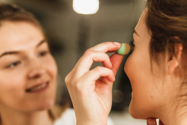 Cut out of woman's face during a professional make-up session where a beauty blender sponge is used.