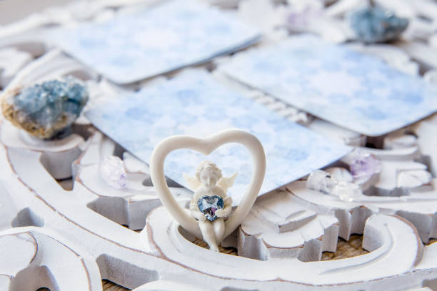 палуба с гаданиями домашние карты ангел на ярко-белый стол, окруженный полу драгоценных камней �кристаллов. селективный акцент на милой фиг� - readings стоковые фото и изображения