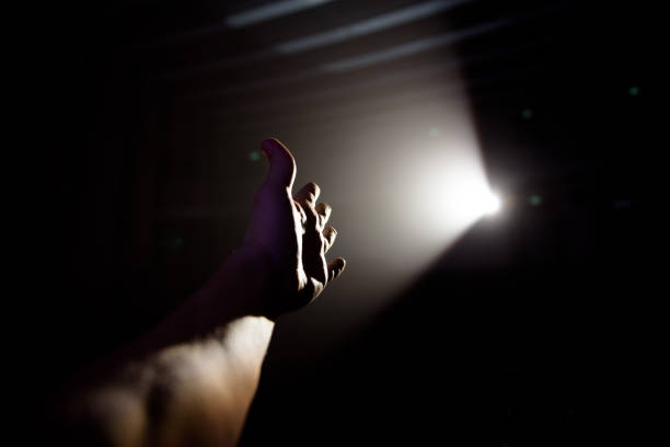 istock Man's hand in a ray of light on a black background. 1211966575