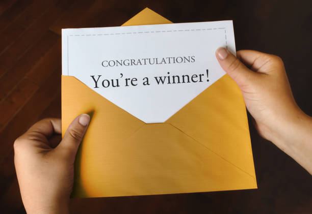 An open shiny gold envelope with a letter that says Congratulations You're a winner! An open shiny gold envelope with a letter that says Congratulations You're a winner! with female hands holding it up junk mail photos stock pictures, royalty-free photos & images