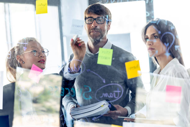 istock Successful business team writing notes at office glass board while discussing together in the coworking space. 1211968256