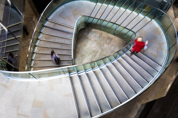 verschwommene bewegung von menschen, die futuristische moderne wendeltreppe hinunterlaufen - spiral staircase circle steps staircase stock-fotos und bilder