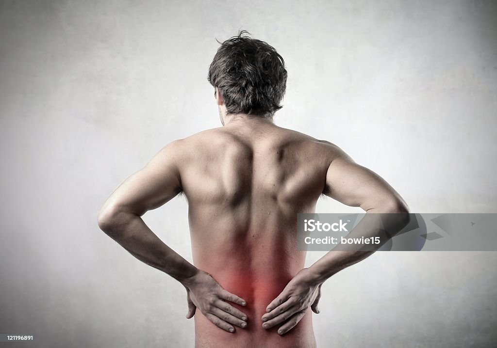 Pain Rear view of a yonug man suffering from backache Adult Stock Photo
