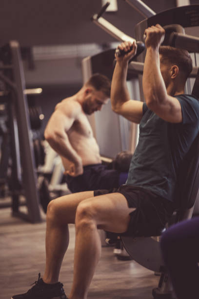 istock Male athlete doing shoulder press exercises at the gym 1211971510