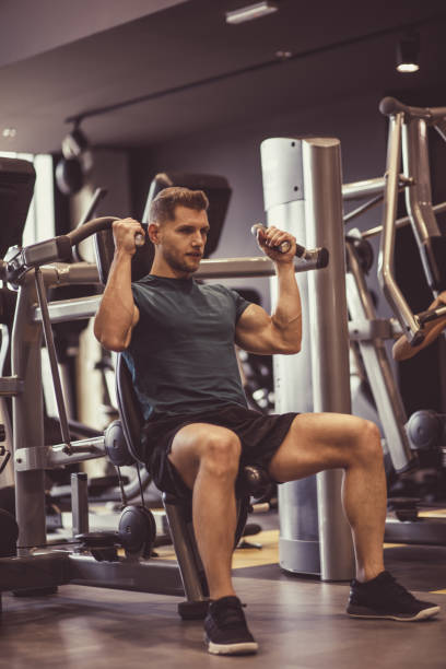 istock Muscular, attractive young man doing shoulder press exercises at the gym 1211971518