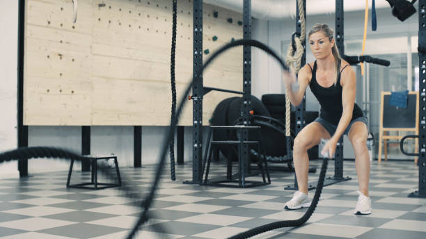 istock Athletic woman training with battle rope 1211971712