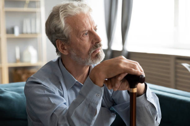 istock Unhappy old man with cane look in distance mourning 1211971854