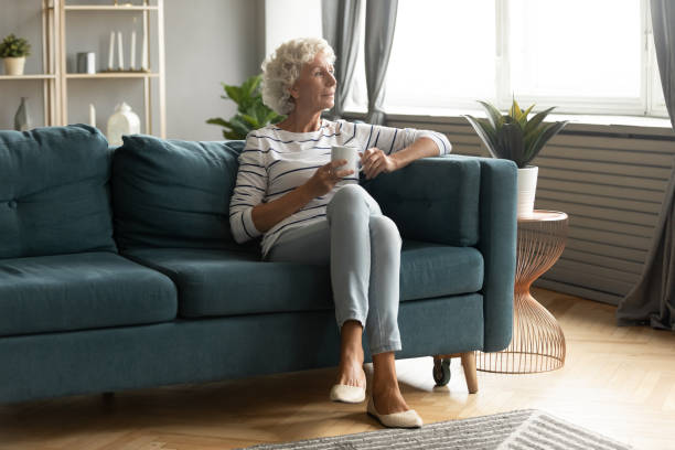 istock Calm mature woman relax on couch drinking tea 1211971864
