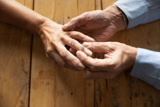 istock Old man put wedding ring on middle-aged woman hand 1211971896