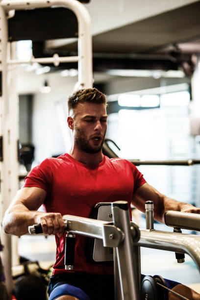 istock Athletic young man building his muscles on exercise machine at the gym 1211972740