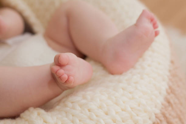istock Close-up of baby's tiny legs on a knitted blanket 1211973111
