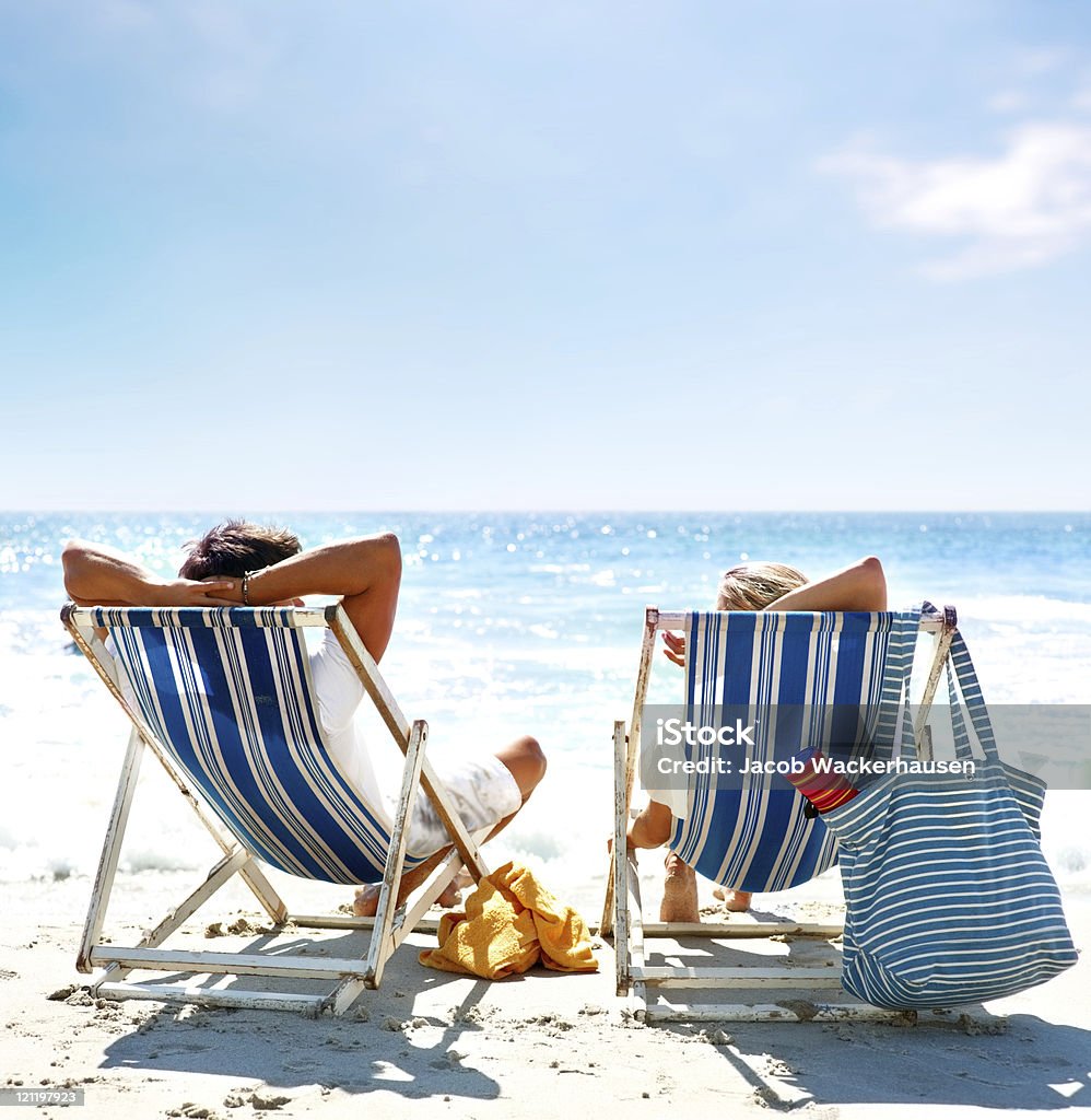 Просмотр пара, сидящая на шезлонги, наслаждаясь отпуска - Стоковые фото Пляж роялти-фри