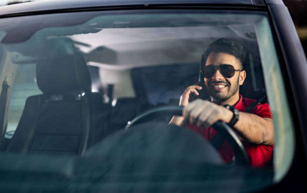istock Happy Young Man Driving And Talking On Phone. 1211979868