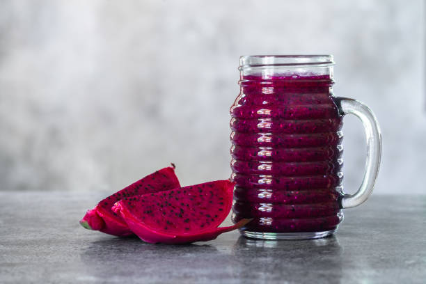istock Fresh smoothie juice from a Dragon fruit (pitahaya) in a glass jar, fruit slices, grey concrete rustic table with copyspace. 1211980040