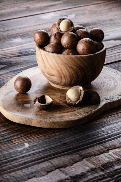 istock Organic ripe whole Macadamia nuts in bowl on old wooden rustic table 1211980299