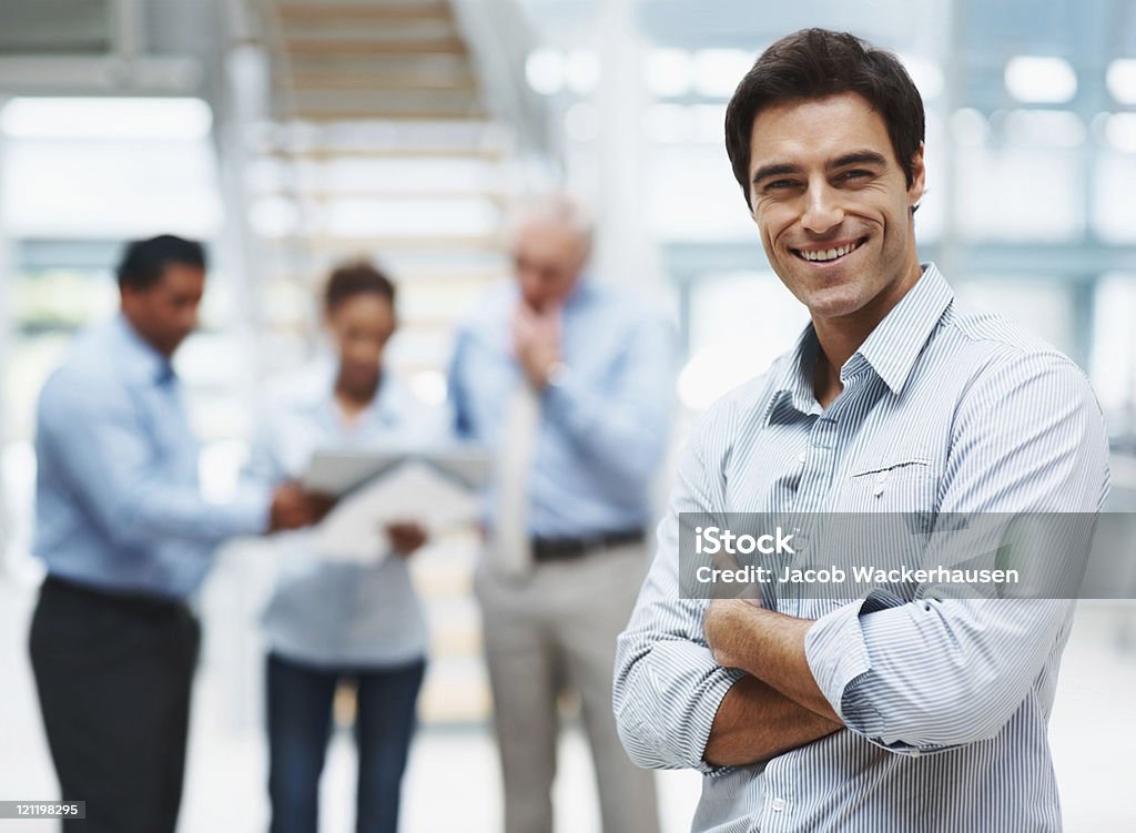 Young executive standing with team mates discussing at the back  Representing Stock Photo