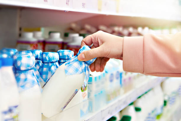 Drinking yogurt in store Drinking yogurt in the hands of a buyer in a store refrigerated section supermarket photos stock pictures, royalty-free photos & images