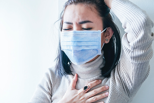 Mujer asiática con protección de mascarilla facial de Coronavirus, con dolor en el pecho photo