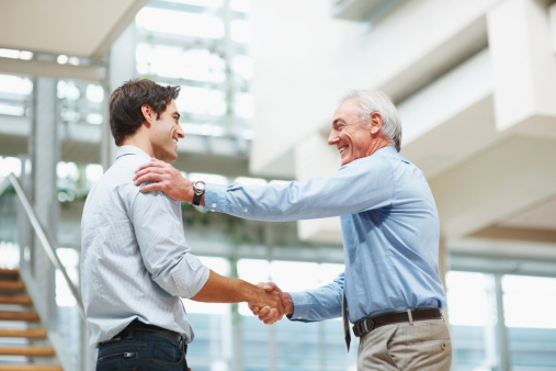 Business agreement - Senior and young executives shaking hands