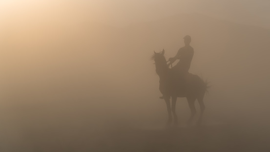 Kayseri, Turkey - November 2019: Unidentified man riding a horse in dust and fog