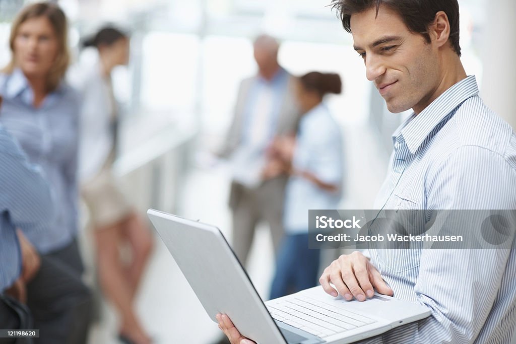 Jovem Empresário usando laptop com os colegas na parte de trás - Foto de stock de 35-39 Anos royalty-free