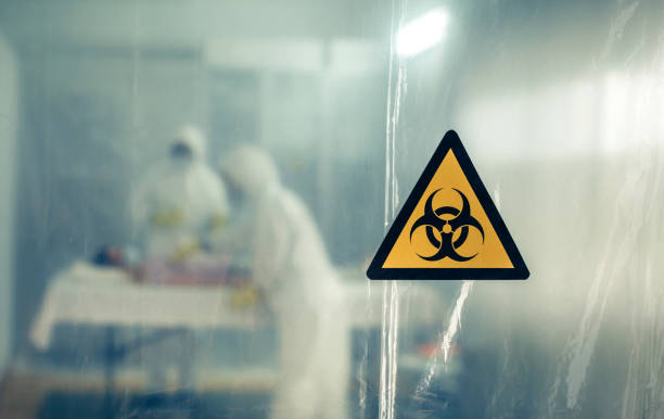 Doctors with bacteriological protection suits attending a patient Unrecognizable doctors with bacteriological protection suits attending a patient infected with a virus biohazard symbol stock pictures, royalty-free photos & images