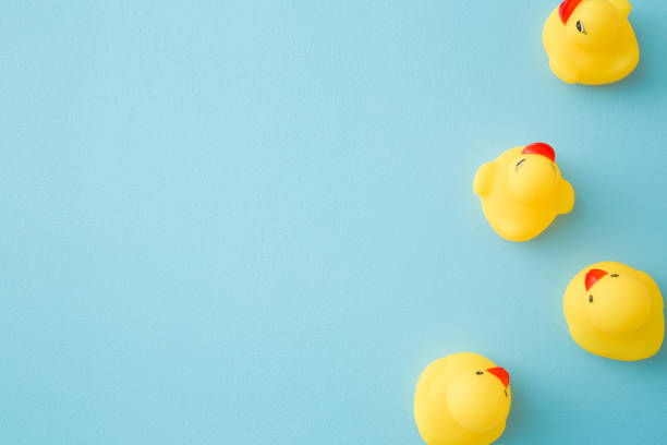 istock Yellow rubber ducklings. Top down view. Empty place for text on light blue background. Pastel color. 1211986475