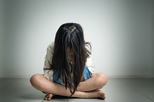 Alone and scared, sad depressed children close her face in the dark room after get bullied