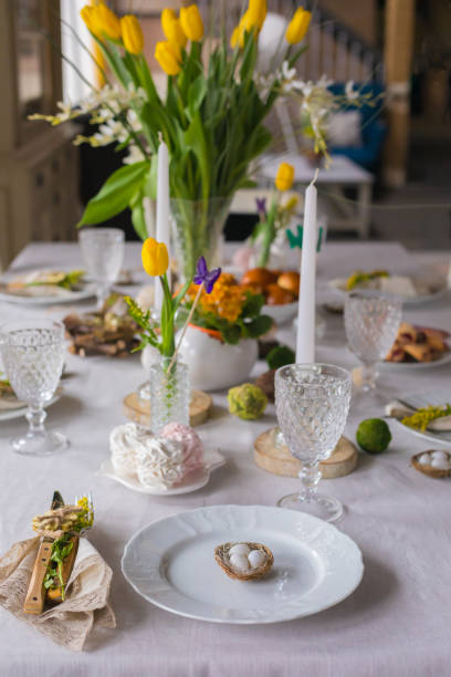 istock Easter festive spring table setting decoration, eggs in nest, fresh yellow tulips, marshmallows, selective focus 1211989578