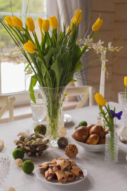 istock Easter festive spring table setting decoration, eggs in nest, fresh yellow tulips, marshmallows, selective focus 1211990114