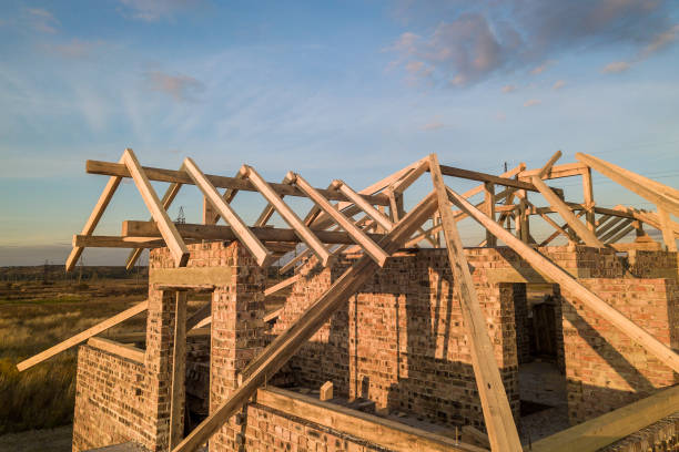 istock Private residential house with wooden roof frame structure under construction. Unfinished brick building under development. 1211992304