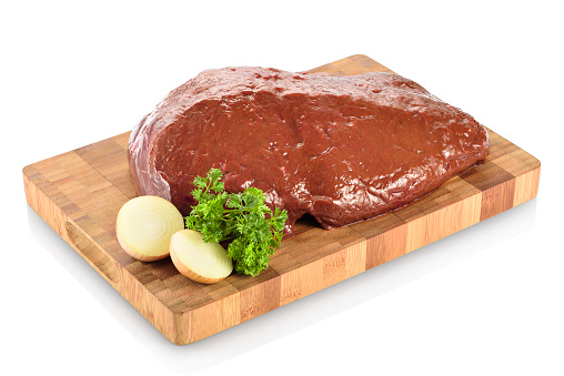 Raw beef liver, ready to be cooked. On a cutting board with chopped onions and parsley aside. Isolated on white background.