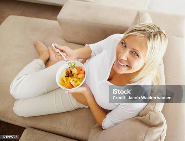 Foto de Vista De Cima De Uma Mulher Madura Relaxante No Sofá Comer e mais fotos de stock de Comer