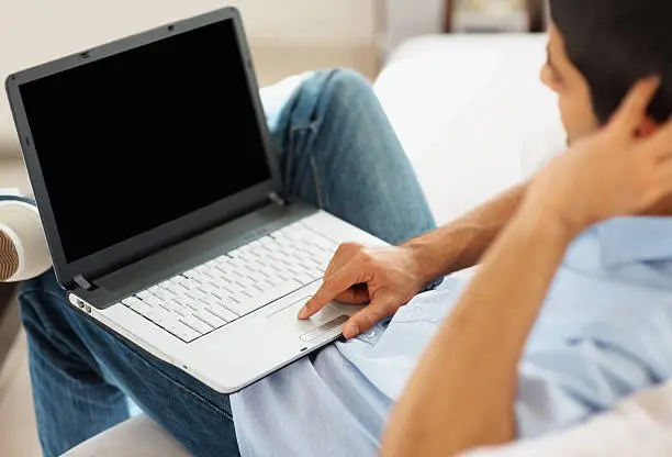 Photo of Closeup of guy working on a laptop indoor