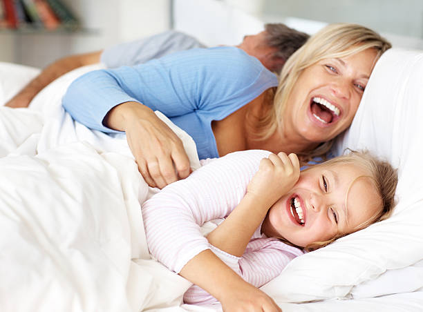 familia feliz divirtiéndose en la mañana en la cama - child laughing blond hair three people fotografías e imágenes de stock