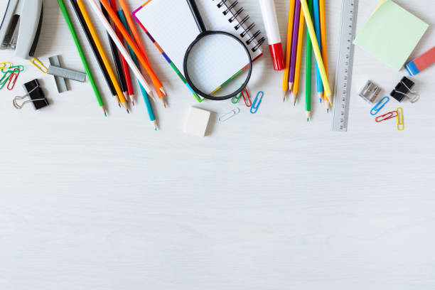 School supplies on white wooden table top view.
