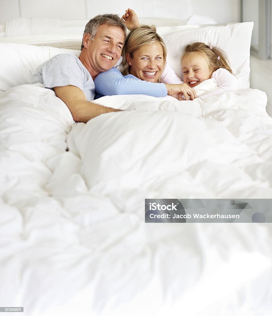 Feliz familia disfrutando de sí mismos en la cama - Foto de stock de Adulto libre de derechos