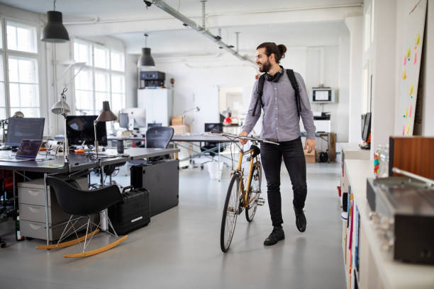 geschäftsmann mit fahrrad im büro - people office mobility looking stock-fotos und bilder