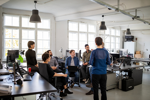 Multi-ethnic group of business people having a staff meeting in open plan office. Corporate workers are planning strategy.