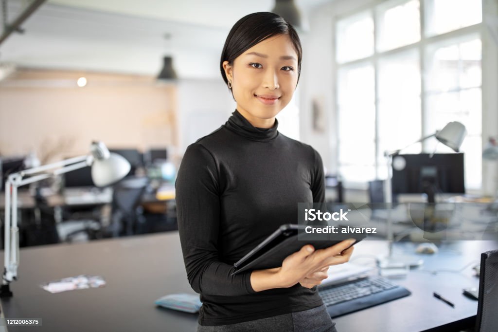 Confident asian businesswoman in office Portrait of young businesswoman standing in office with a digital tablet. Confident asian businesswoman in office. Women Stock Photo