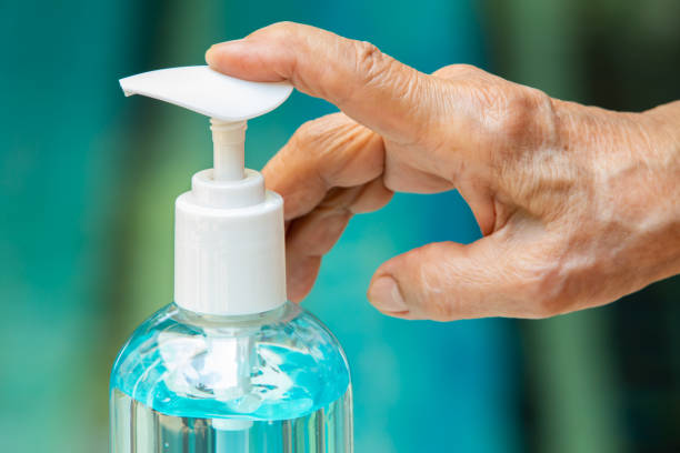 Senior woman's hands is pressing bottle of sanitizer gel pump dispenser to wash her hands in blue pool background, Close up & Macro shot, Select focus, Prevention from covid19, Bacteria, healthcare concept manos de mujer mayor está presionando botella de dispensador de bomba de gel desinfectante para lavarse las manos en el fondo azul de la piscina, de cerca & macro tiro, seleccione enfoque, prevención de covidente19, bacterias, concepto de atención médi