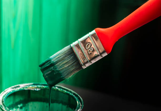 brushes and an open can with red on a plain gray background