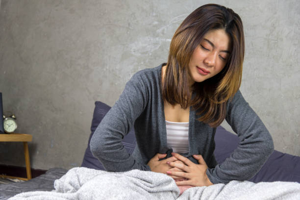 Woman with with menstrual pain problem concept. Woman sitting on Bed and feeling spasm and symptoms of pms. polycystic ovary syndrome photos stock pictures, royalty-free photos & images