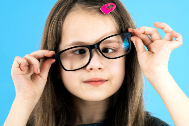 파란색 배경에 고립 된 안경을 쓰고 있는 십자가 눈의 어린이 여학생의 초상화를 클로즈업합니다. - cross eyed 이미지 뉴스 사진 이미지