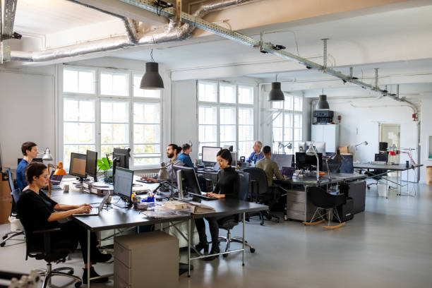 Busy modern open plan office with staff Casually dressed workers in a busy open plan office. Business people working at a modern office. open plan stock pictures, royalty-free photos & images