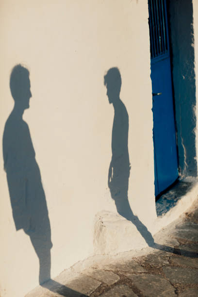 istock Shadows on wall of two men talking in street 1212013921