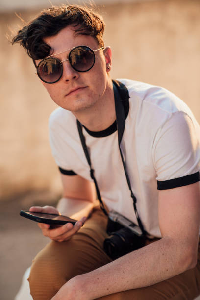 istock Male tourist in sunglasses looking at camera and using phone 1212014452