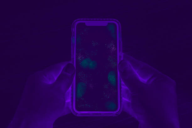 Invisible germs and bacteria on smartphone screen exposed by UV Blacklight inspection stock photo